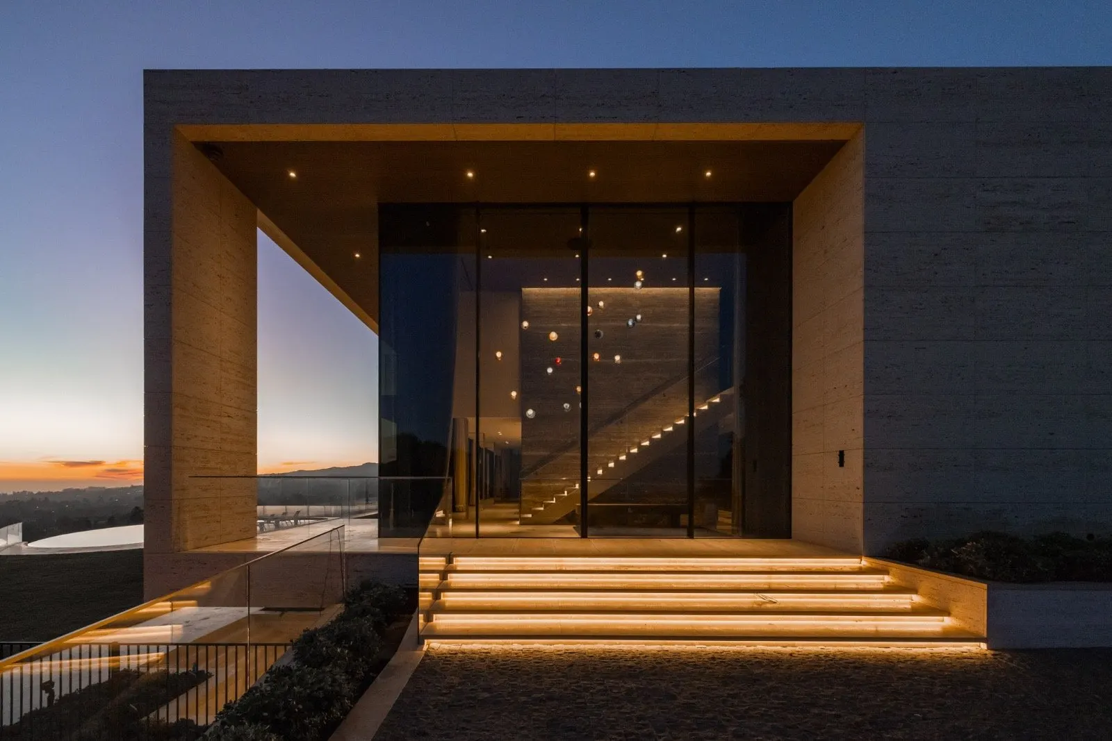 The Getty House — 684 Firth Brentwood CA LA Exterior Travertine Entry Dusk Glass Facade Illuminated Steps  Modern Home