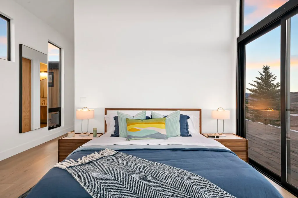 Icon Haus — bedroom with wood headboard and sliding glass door to the mountains