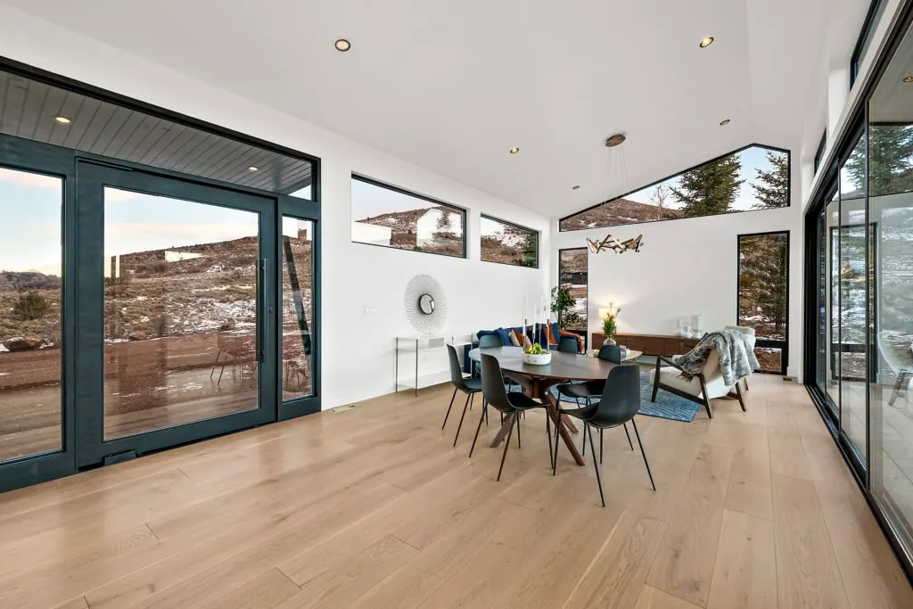 Icon Haus — vaulted dining and living space with black-framed doors and hardwood floors