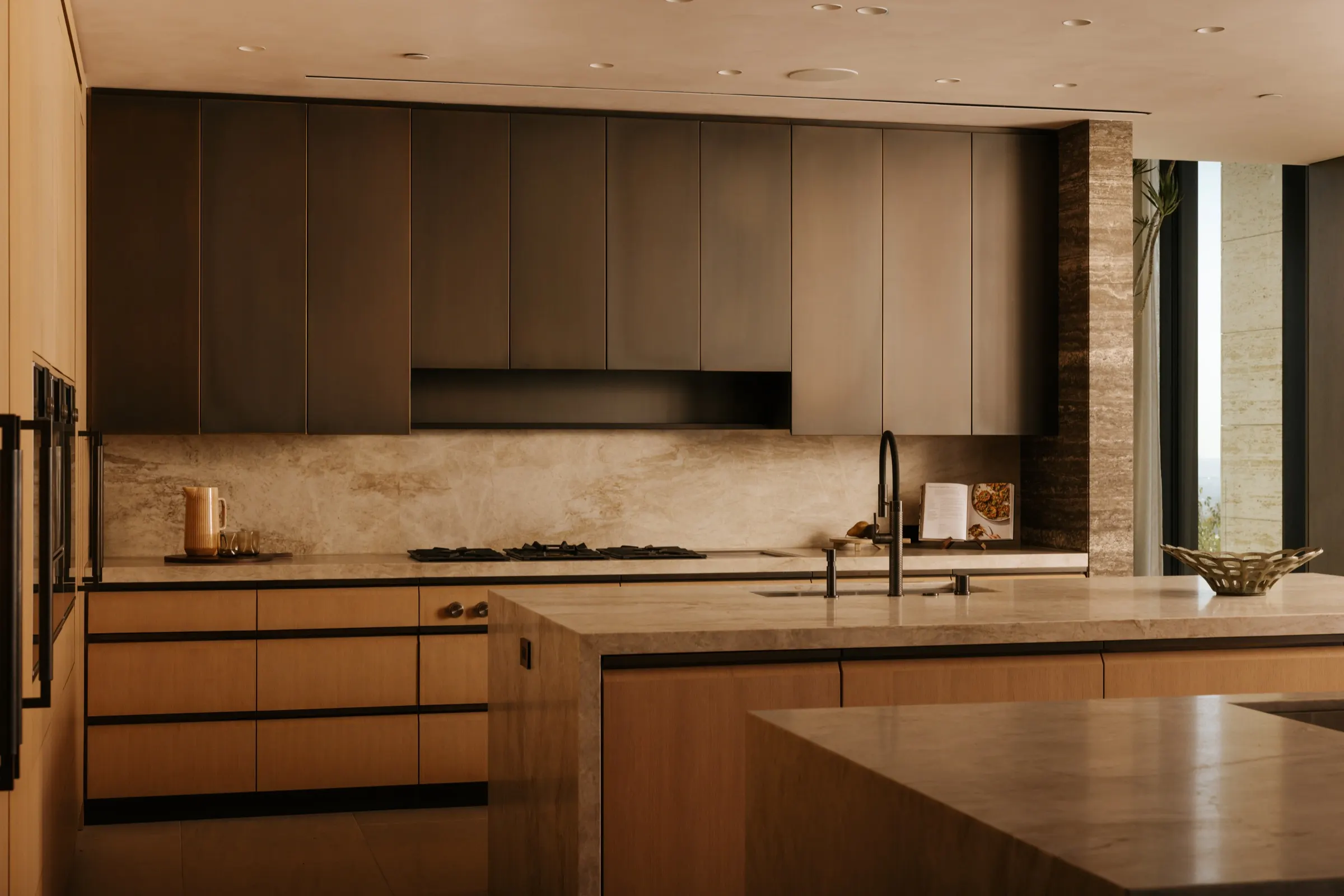 The Getty House, Brentwood — kitchen range wall in dark cabinetry with stone backsplash