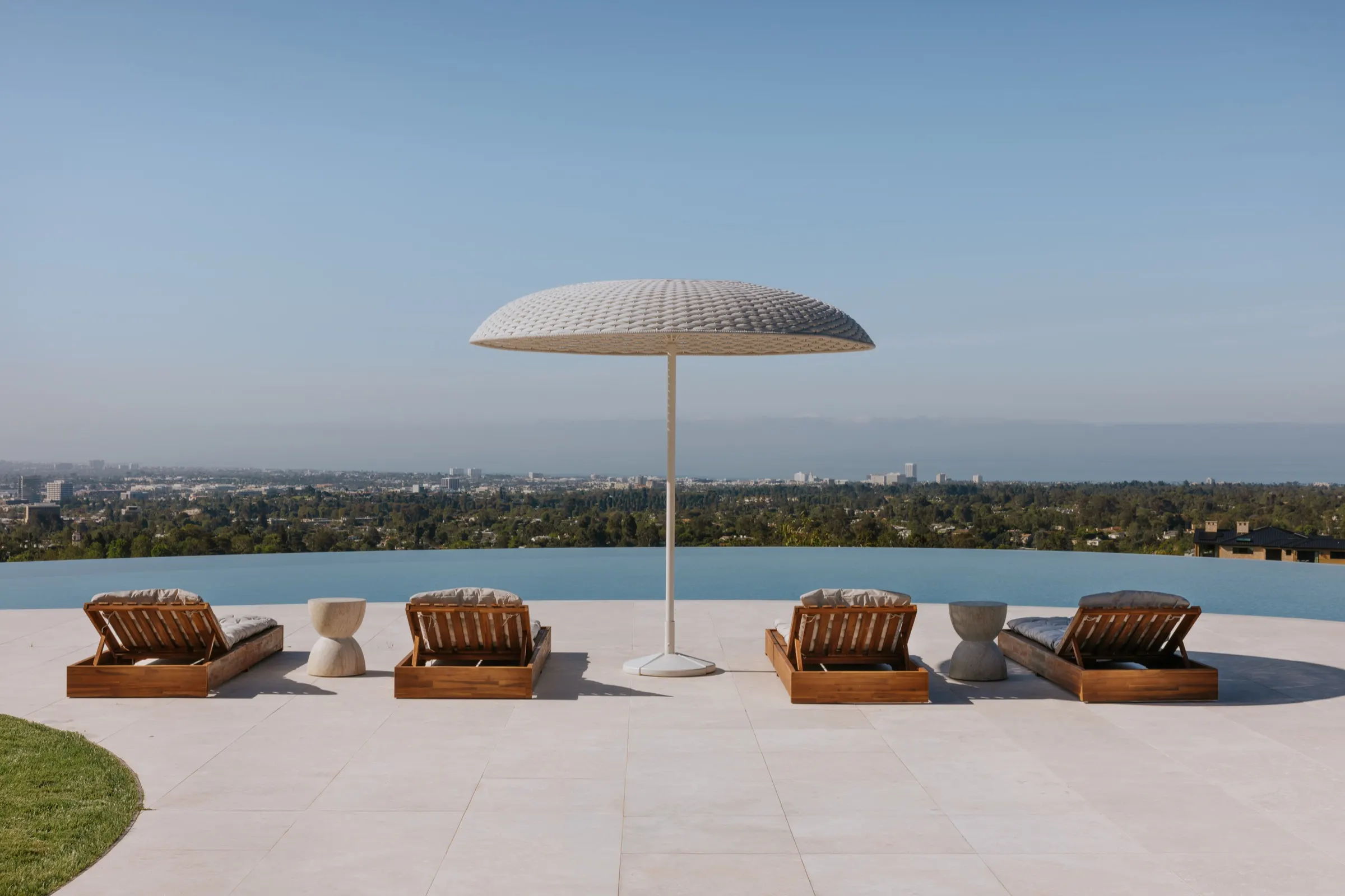 The Getty House, Brentwood — pool terrace with loungers and the Pacific beyond