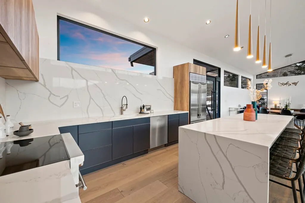 Icon Haus — quartz waterfall island beneath the kitchen picture window