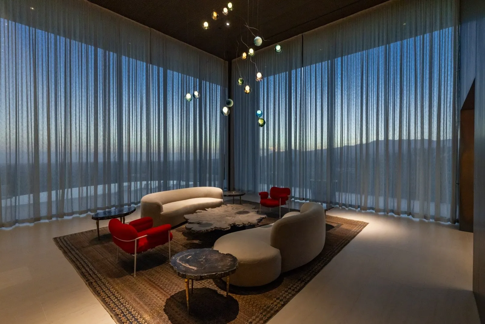 Getty House — lounge with curved sofas and organic chandelier at sunset