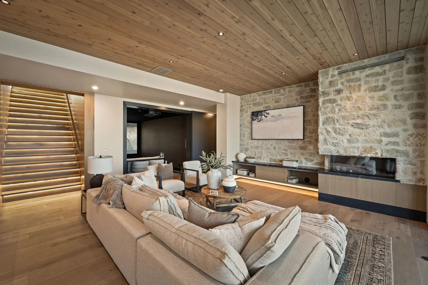 Linear fireplace set into the stone wall beside the floating stair at Lumen