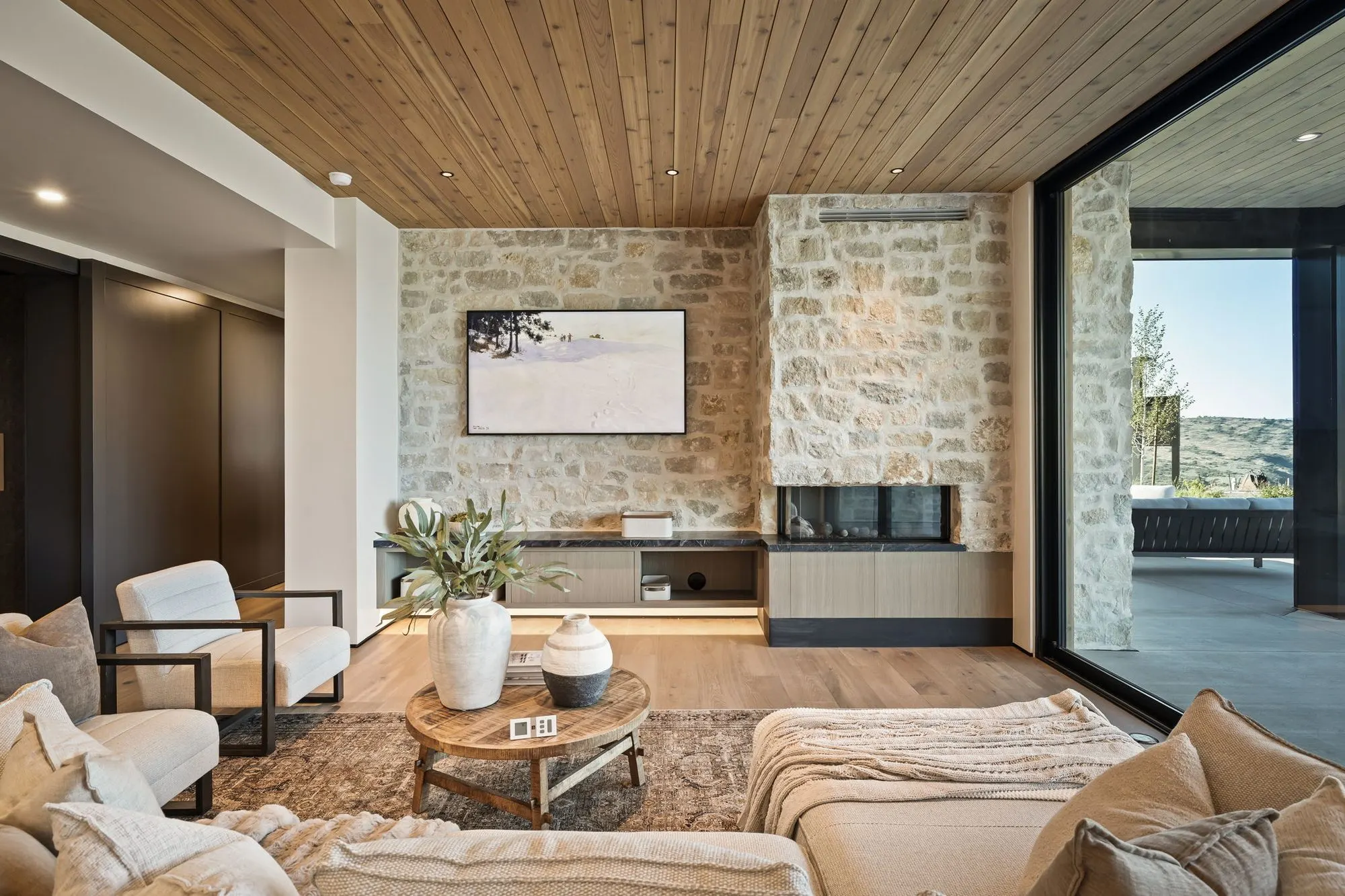 Lumen — lower-level lounge with a stone accent wall and glass to the patio