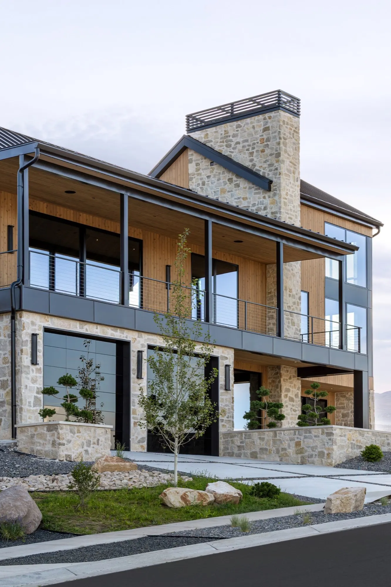 Lumen — covered deck over stone base at dusk with sculpted evergreens