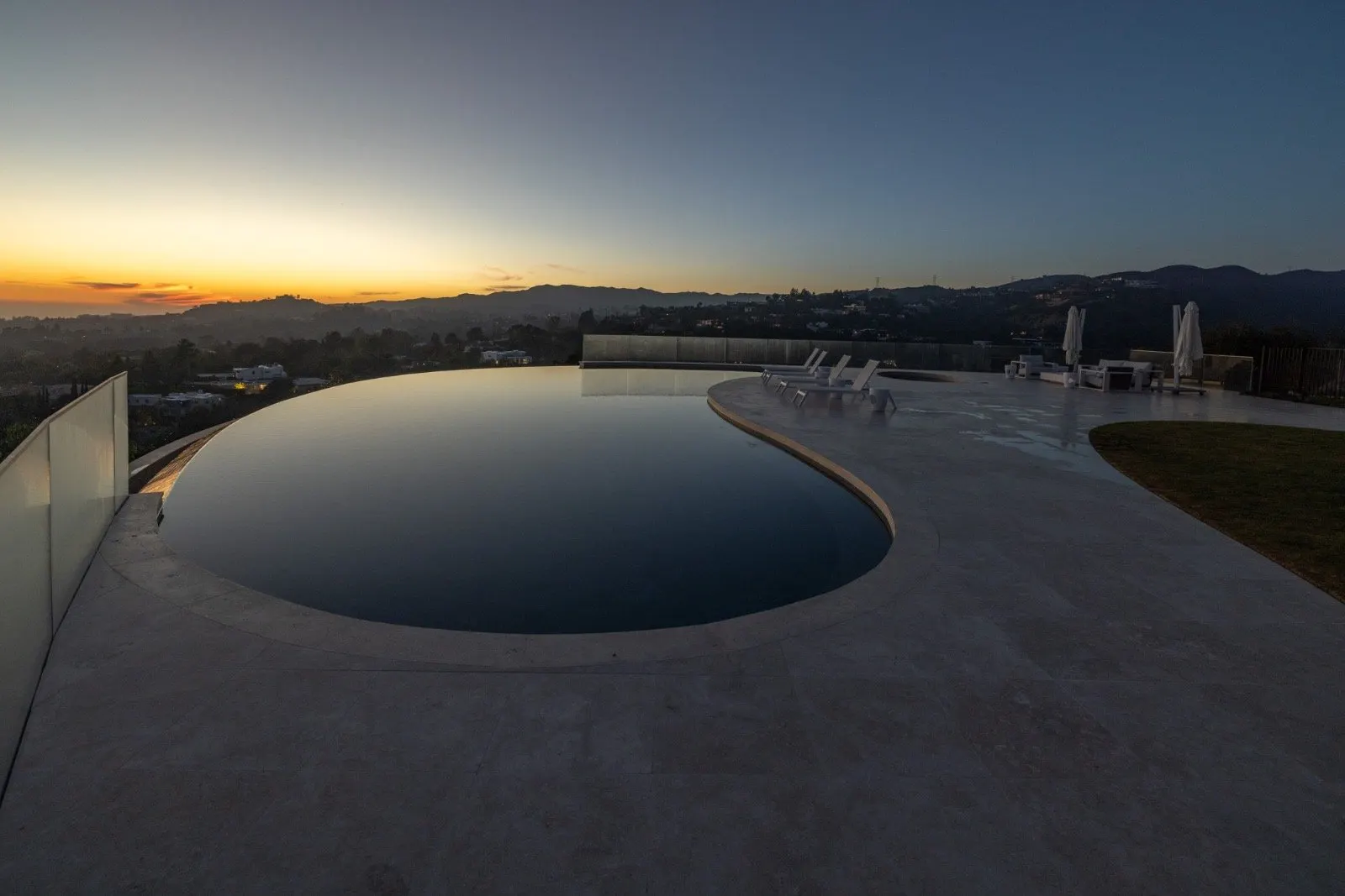 Getty House — infinity pool at dusk, horizon view over the travertine deck