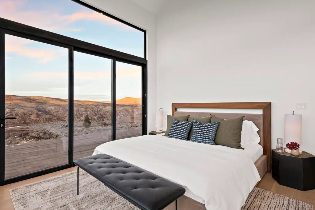 Icon Haus — master suite with wood headboard and sliding glass door to the hillside