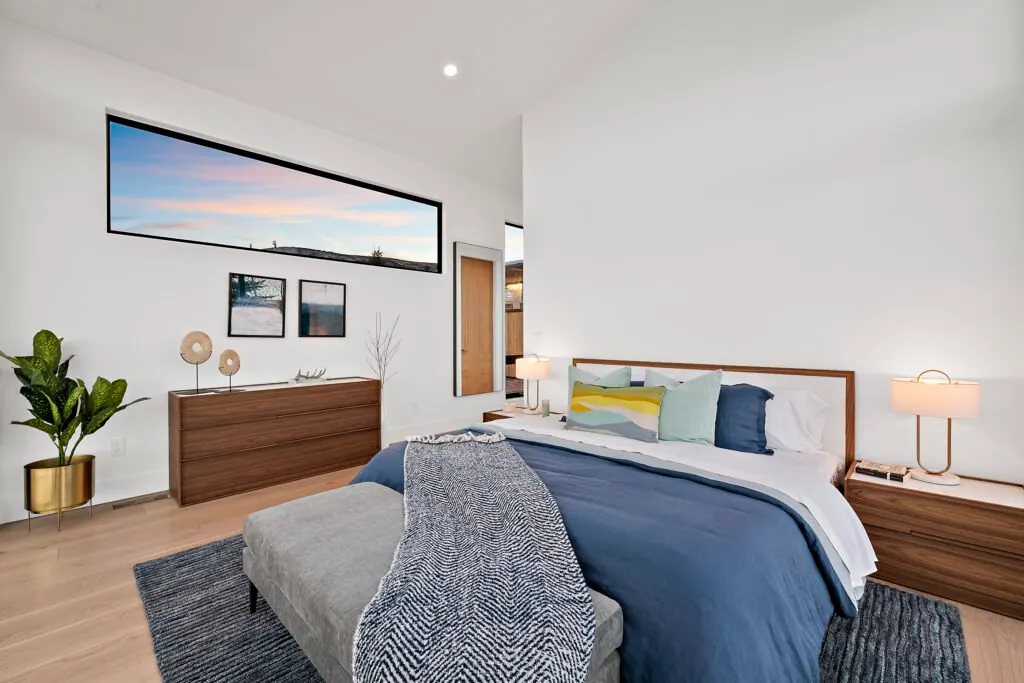 Icon Haus — guest bedroom with wood dresser and picture window to the landscape