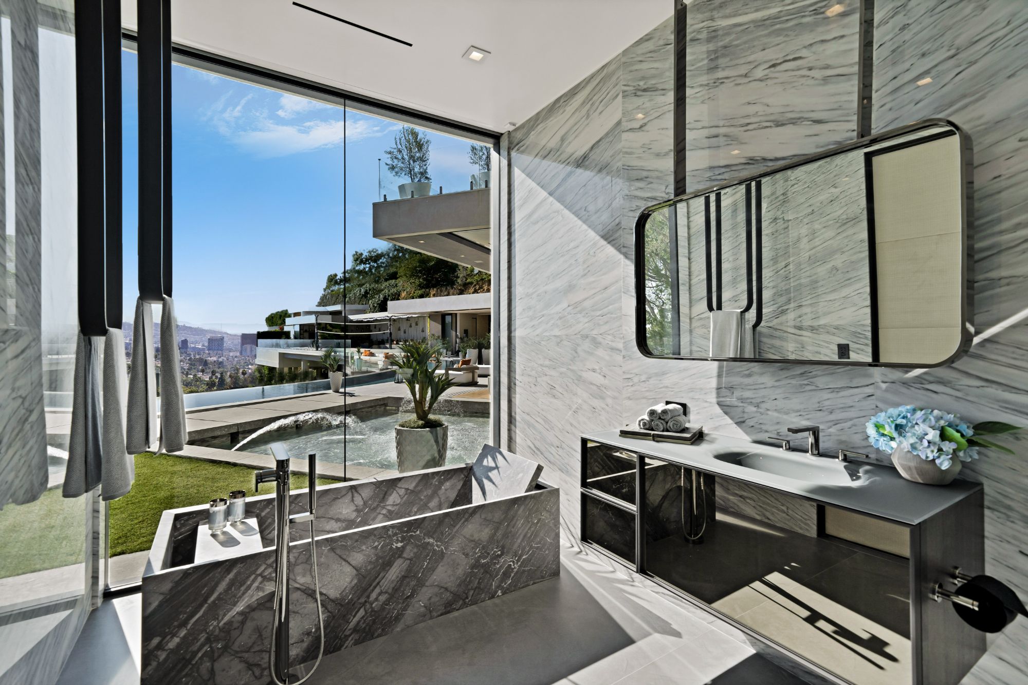 Flicker Estate — primary bath, soaking tub at the glass with the city beyond