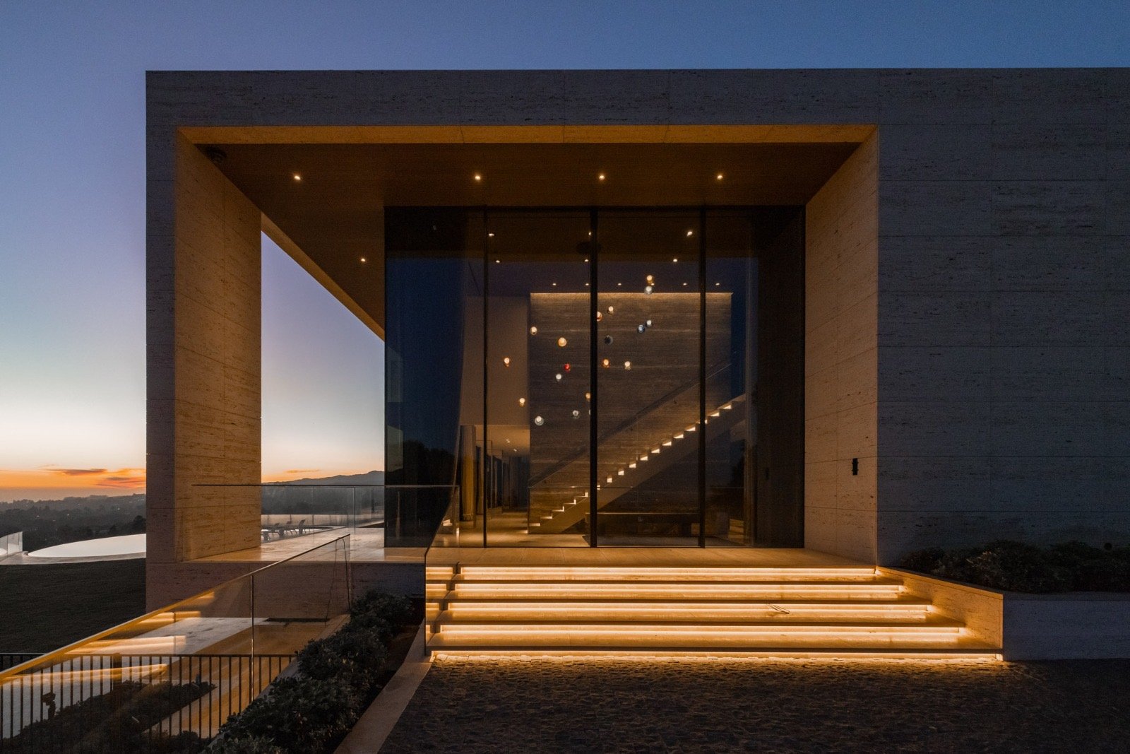 The Getty House — 684 Firth Brentwood CA LA Exterior Travertine Entry Dusk Glass Facade Illuminated Steps  Modern Home
