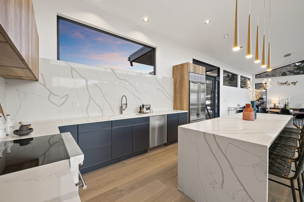 Icon Haus — quartz waterfall island beneath the kitchen picture window