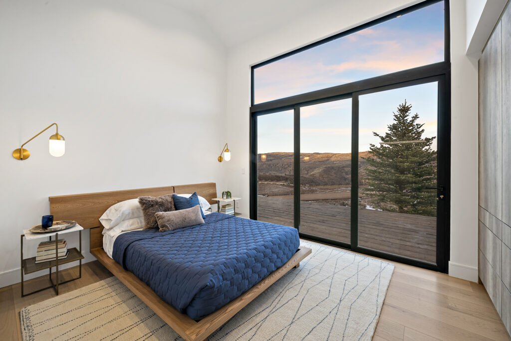 Icon Haus — master bedroom with platform bed and brass sconces overlooking the hills