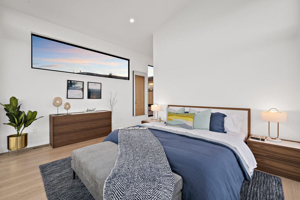 Icon Haus — guest bedroom with wood dresser and picture window to the landscape