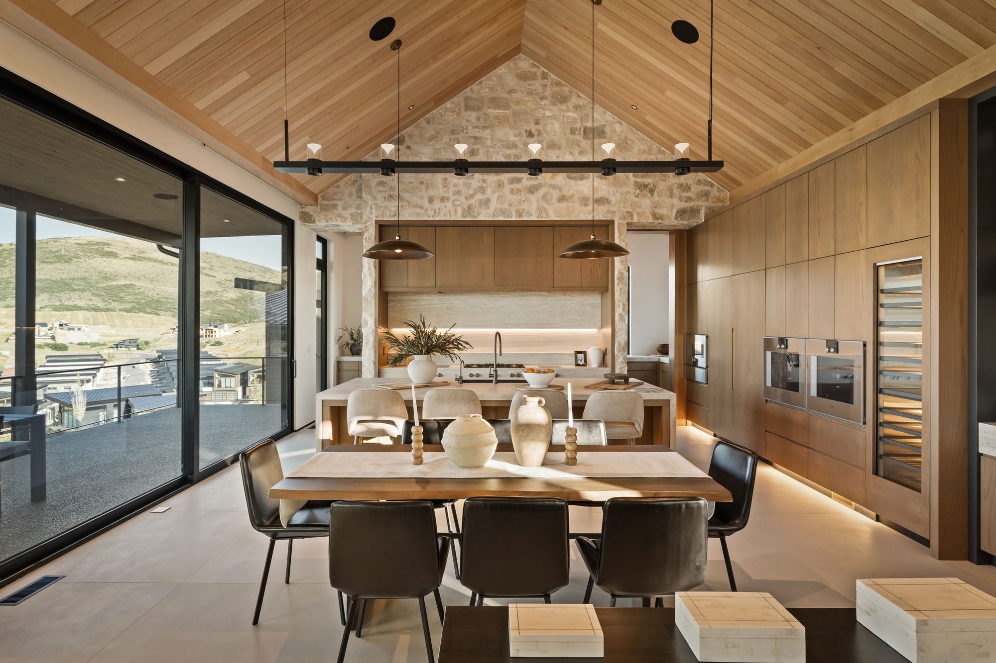 Lumen — dining under the vaulted cedar ceiling with a linear pendant