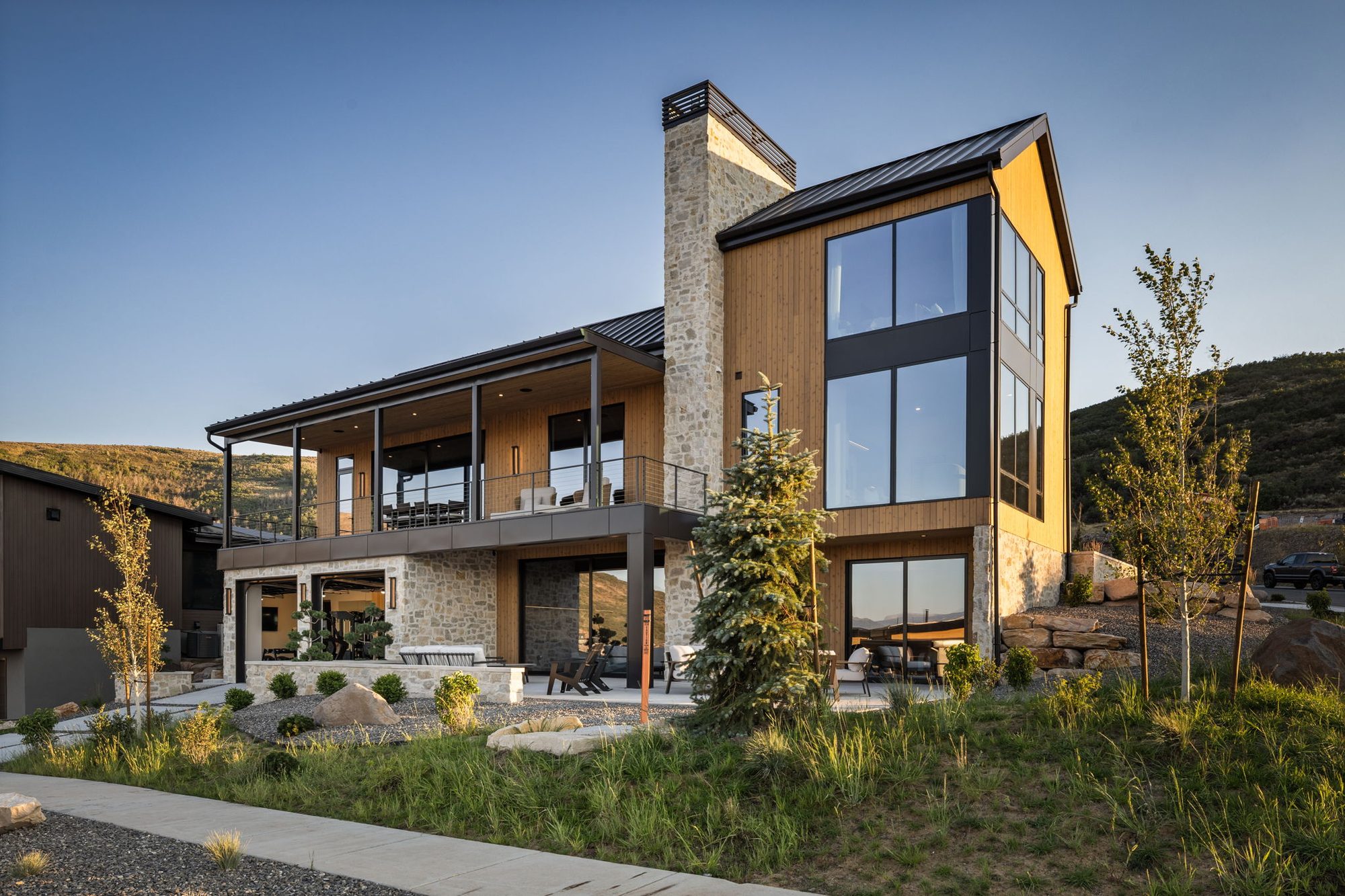Lumen rear elevation — stone chimney, decks, and glass, by Roderick Builders