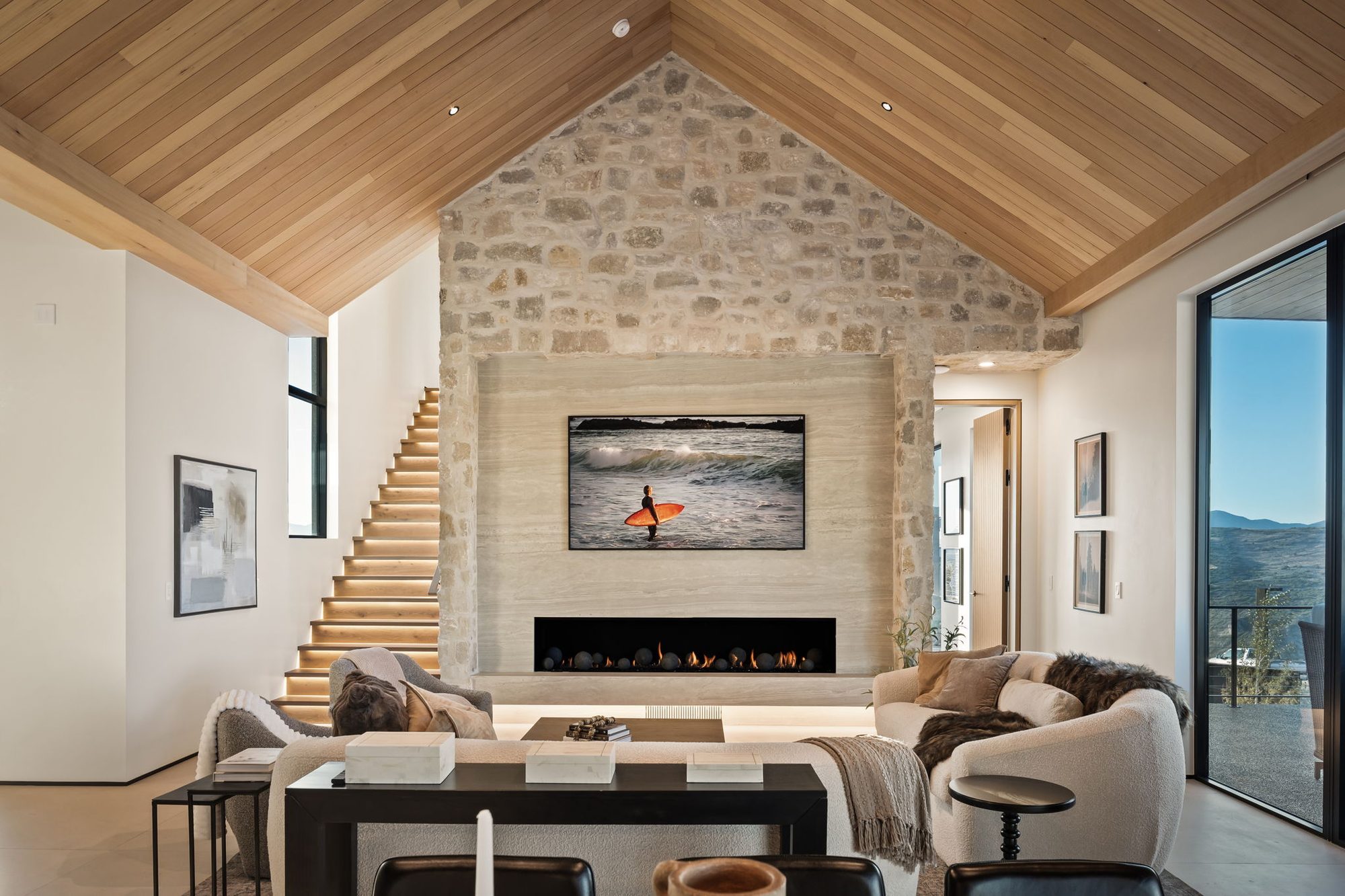 Lumen great room — stone fireplace and glass on both ends, by Roderick Builders