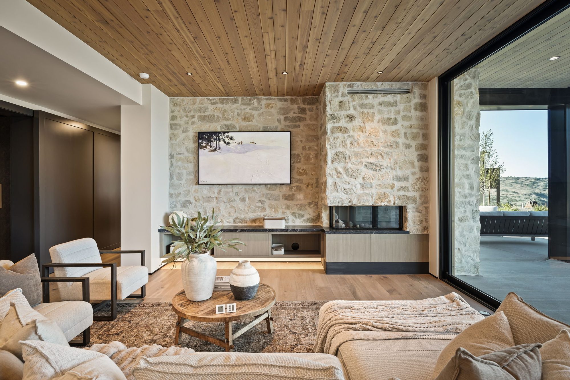 Lumen — lower-level lounge with a stone accent wall and glass to the patio