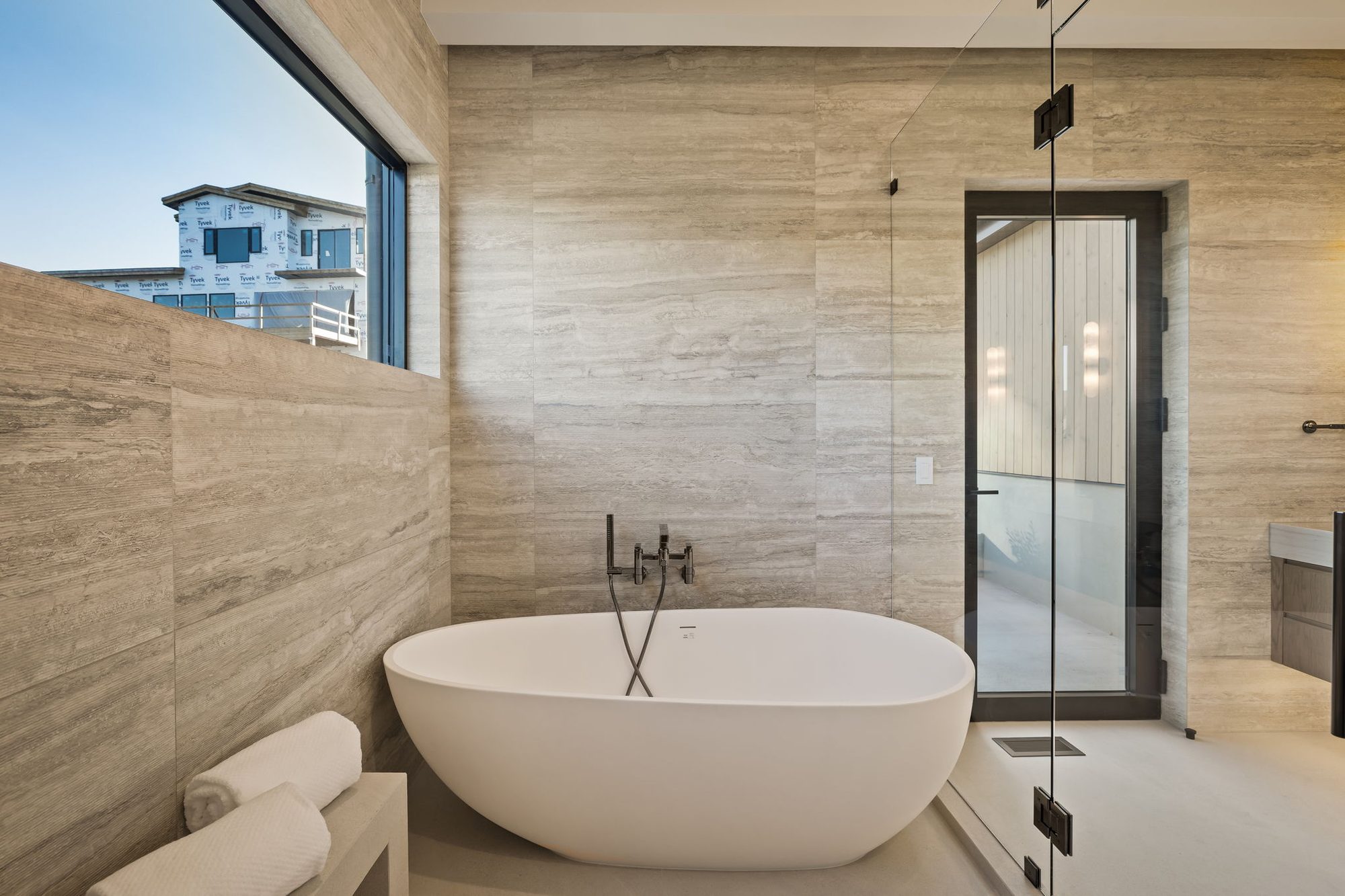 Lumen primary bath with freestanding tub against limestone