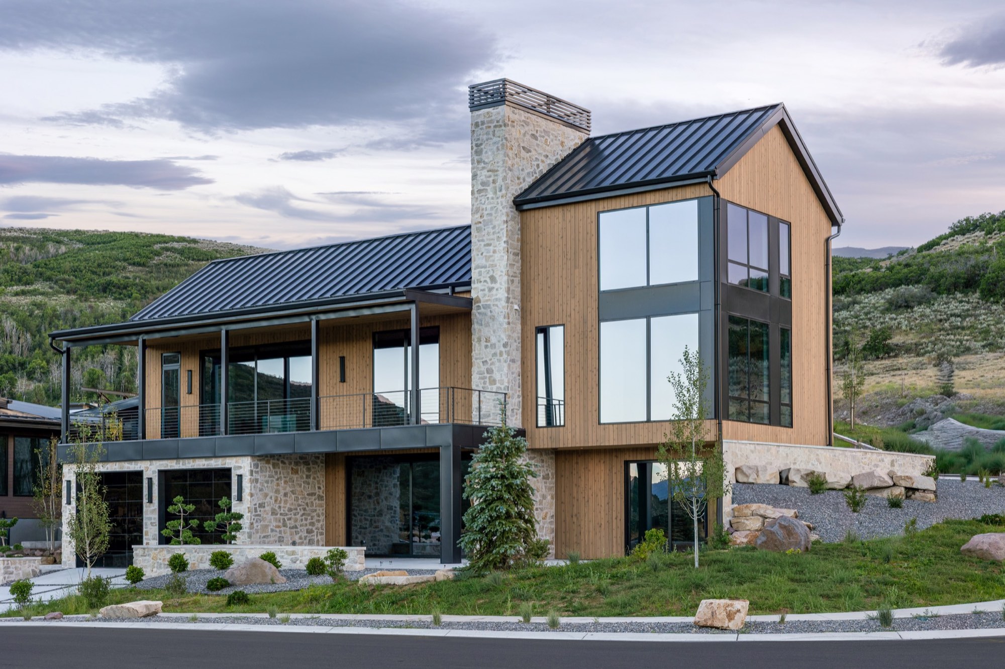 Lumen — rear elevation with stone chimney and double-height glass