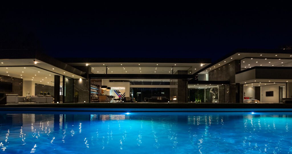 Stradella — primary suite wrapped in floor-to-ceiling glass overlooking Los Angeles